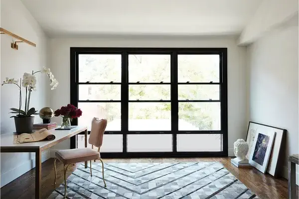hung windows macfarlane (1) Classic single hung windows from MacFarlane Windows and Doors, showin in a modern home with a desk, rug, and painting on the floor.