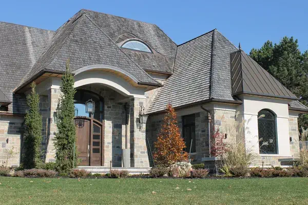 decorative windows and doors macfarlane (1) Modern home exterior showcasing a large bay window and an elegant entrance door, surrounded by greenery, highlighting quality craftsmanship by MacFarlane Windows and Doors.