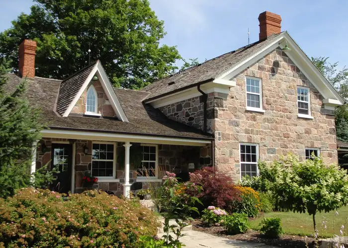 MacFarlane Home Windows and Doors A large home showcasing bright new vinyl windows and a white trim feature, a cottage style home.